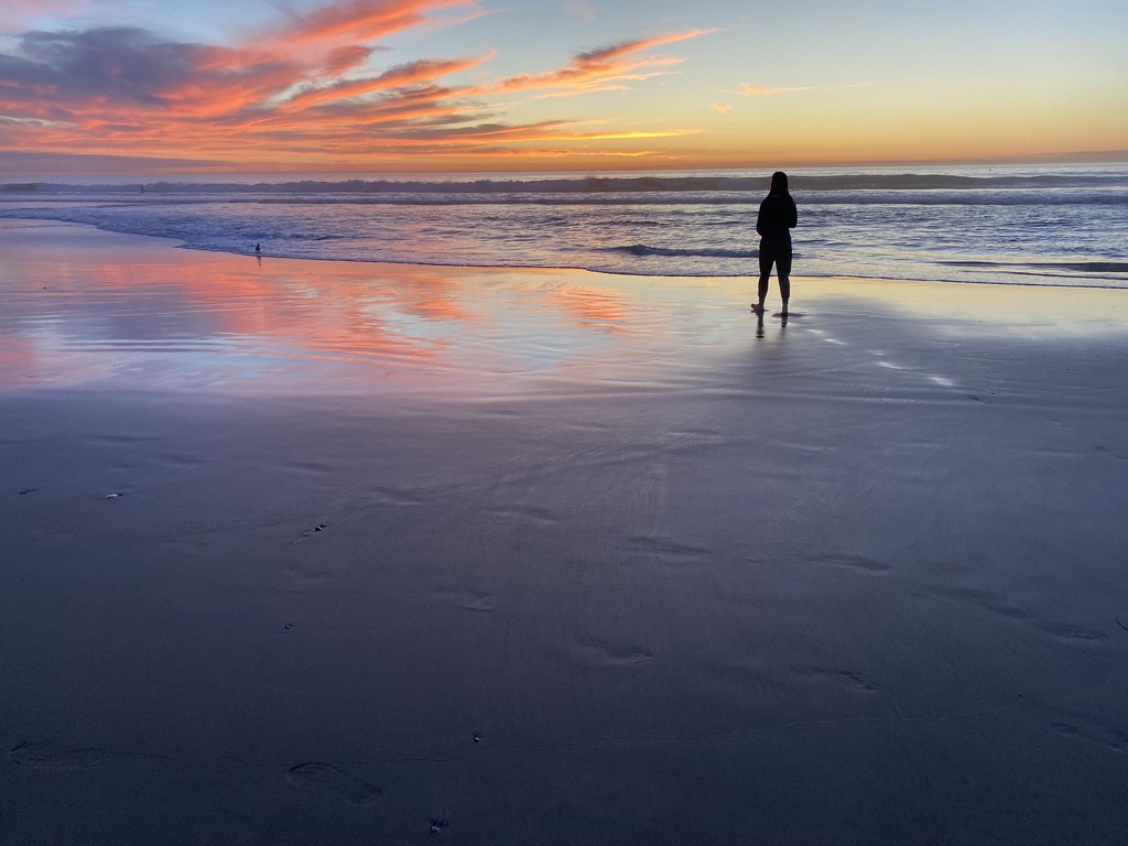 Ajna standing on the beach at sunset